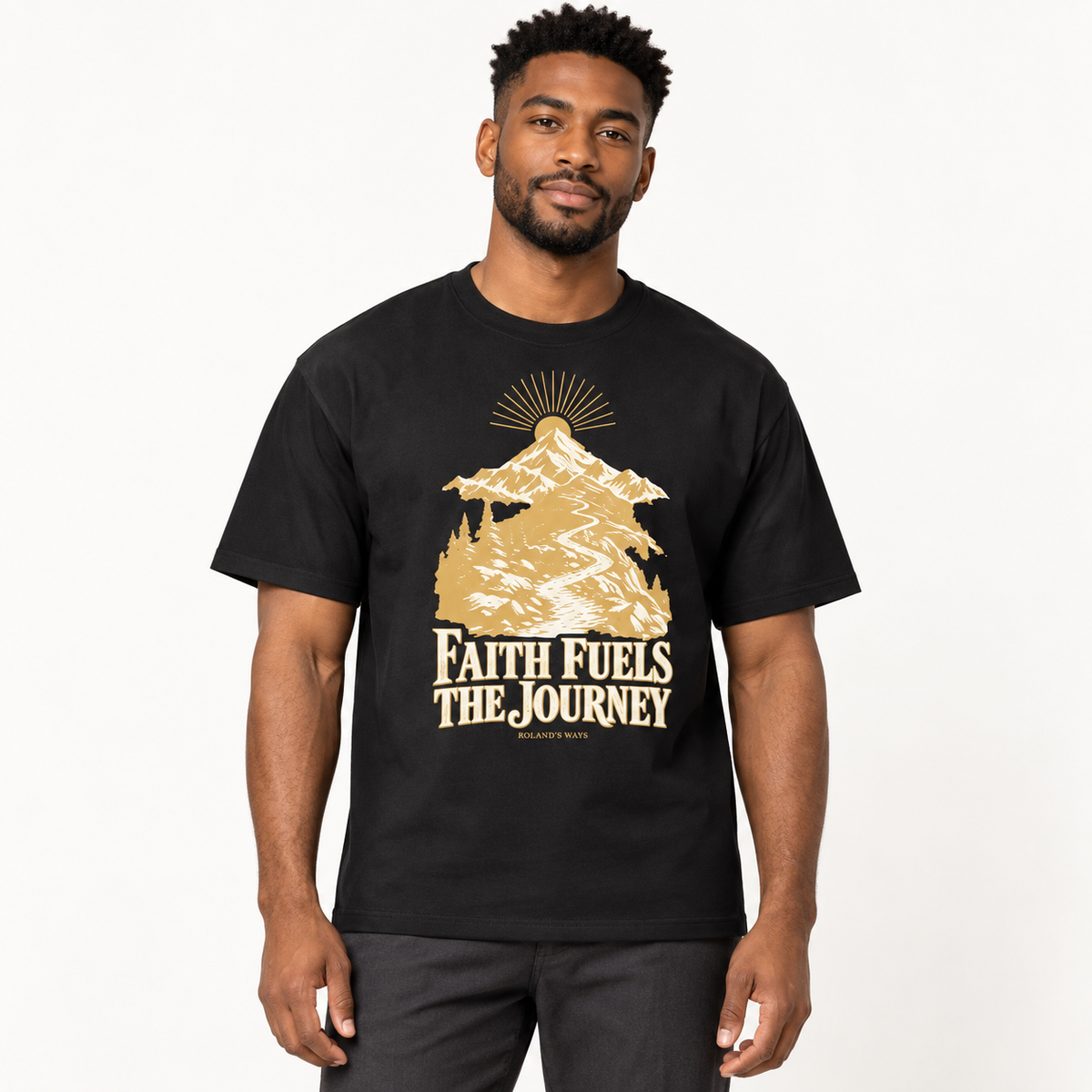 AI studio mockup of a man wearing the black Faith Fuels the Journey T-shirt with gold and ivory mountain artwork.