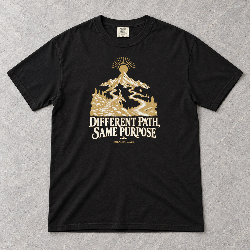 AI styled flat-lay mockup on slate: the black Different Path, Same Purpose T-shirt with gold and ivory mountain artwork.