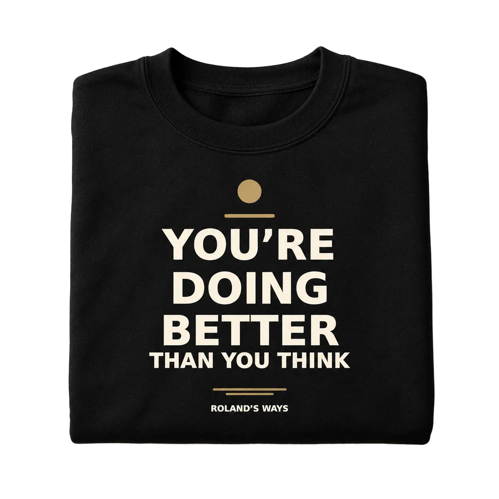 Folded black crewneck showing the full You’re Doing Better Than You Think design and Roland’s Ways signature.