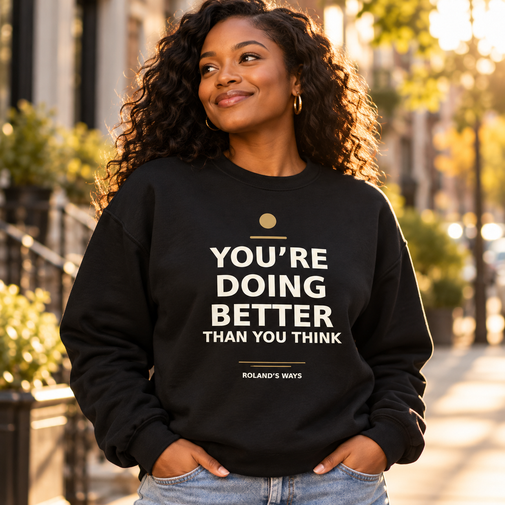 Model wearing the black You’re Doing Better Than You Think crewneck on a sunlit sidewalk.